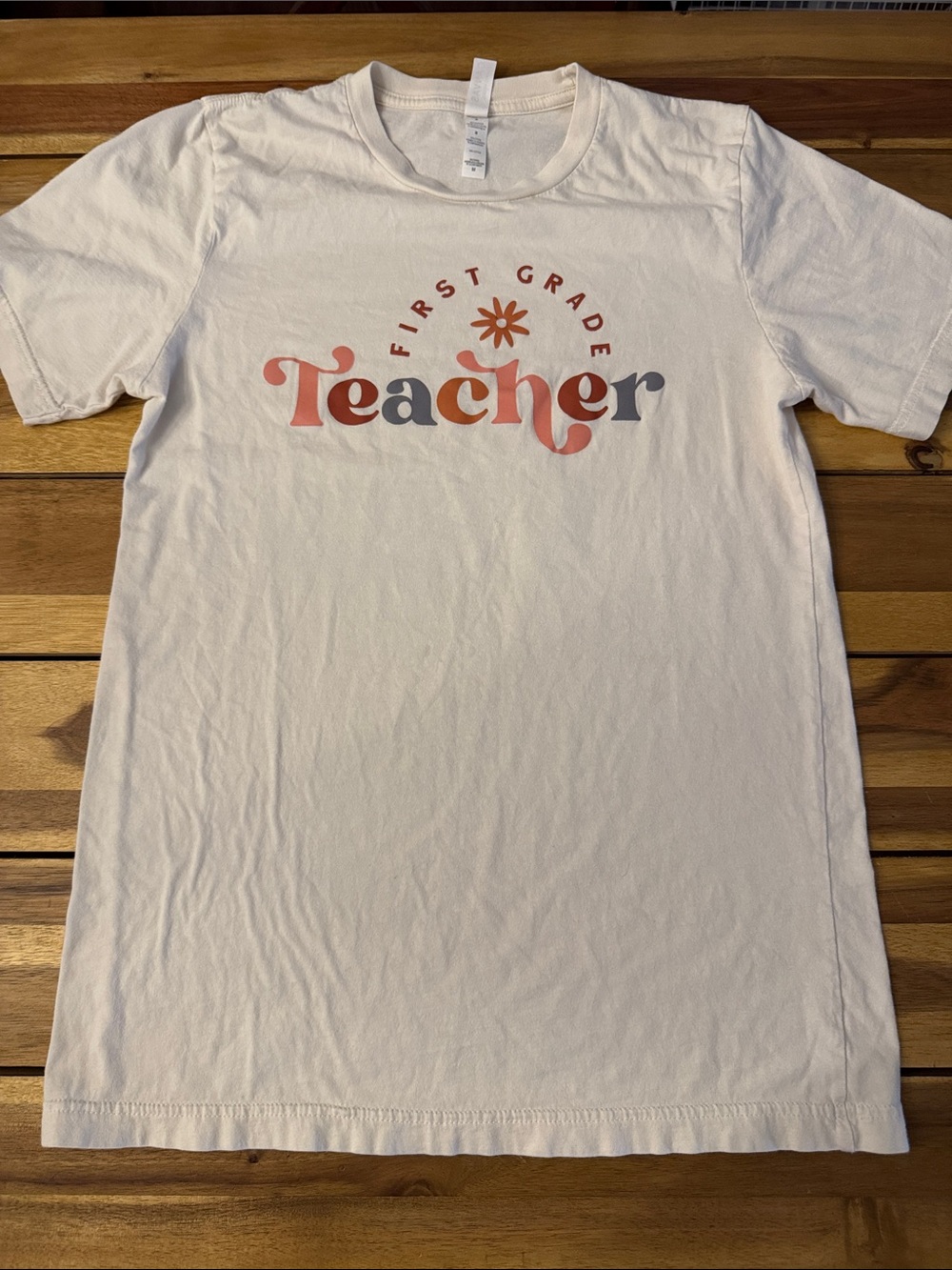 Bella Canvas White First Grade Teacher Graphic Tee with Multicolor Lettering